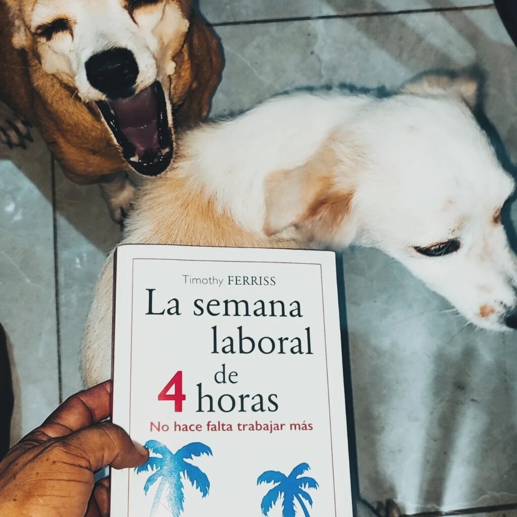 una mano sostiene el libro semana laboral 4 horas, mascotas se ven de fondo